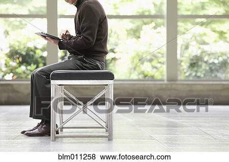 Stock Photo - Asian businessman using digital tablet in lobby. Fotosearch