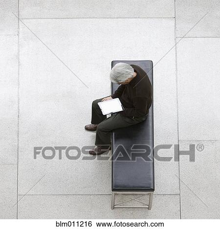 Stock Photograph - Asian businessman using digital tablet in lobby. Fotosearch