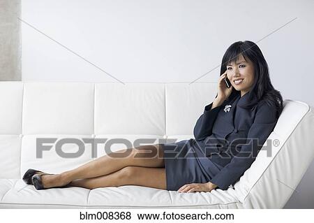 Asian businesswoman with feet up talking on cell phone View Large Photo Image Stock Photo - Asian businesswoman with feet up talking on cell phone. Fotosearch