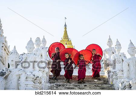 Picture - Asian children with parasols balancing on Buddhist shrine. Fotosearch
