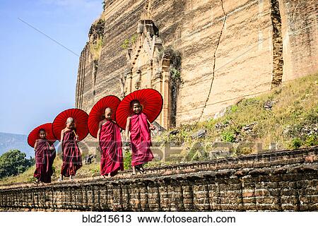 Stock Image - Asian children with parasols balancing on stone wall. Fotosearch