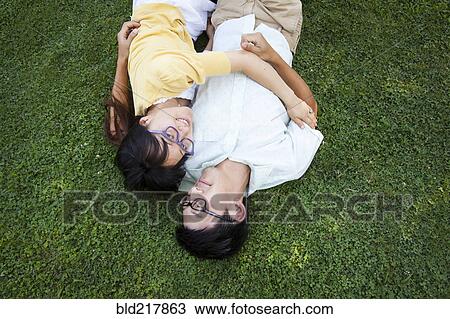 Stock Image - Asian couple hugging on grass. Fotosearch