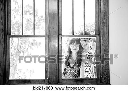 Stock Image - Asian couple looking through window. Fotosearch