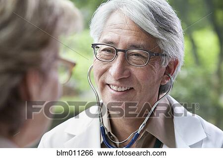 Stock Photograph - Asian doctor examining patient. Fotosearch