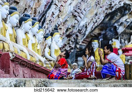 Stock Image - Asian family praying at Buddha temple. Fotosearch