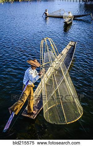 Stock Photography - Asian fisherman fishing in canoe on river. Fotosearch