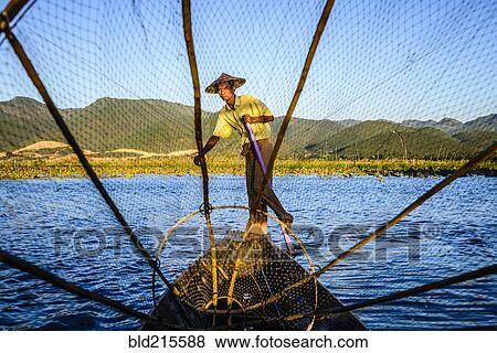 Stock Photo - Asian fisherman using fishing net in canoes on river. Fotosearch
