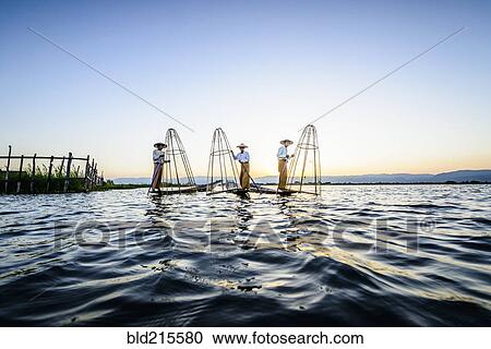 Stock Image - Asian fishermen fishing in canoes on river. Fotosearch