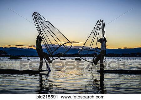 Stock Image - Asian fishermen using fishing nets in canoe on river. Fotosearch