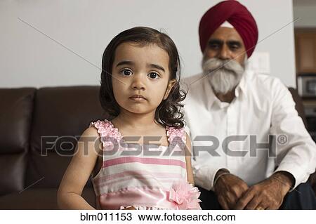 Stock Image - Asian girl in living room with grandfather. Fotosearch