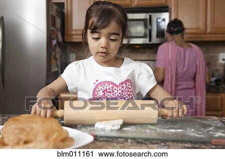 Asian girl rolling out dough in kitchen View Large Photo Image Stock Image - Asian girl rolling out dough in kitchen. Fotosearch