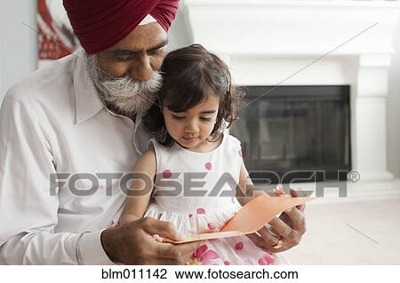 Stock Image - Asian grandfather reading book to granddaughter. Fotosearch