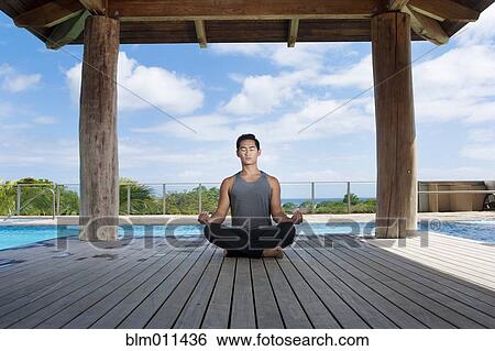Stock Photograph - Asian man practicing yoga at poolside. Fotosearch