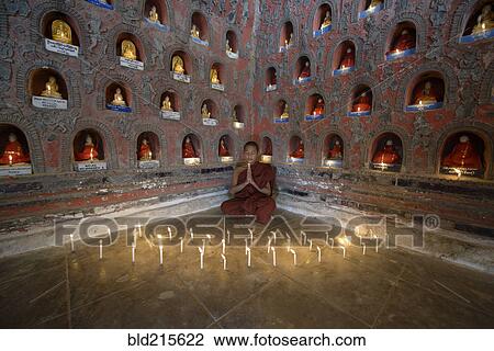 Stock Image - Asian monk-in-training praying in ancient temple. Fotosearch