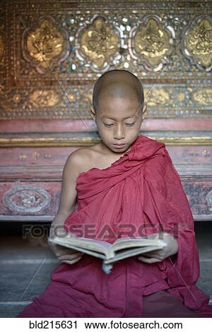 Stock Image - Asian monk-in-training reading book in temple. Fotosearch