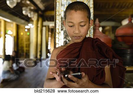 Asian monk-in-training using cell phone indoors View Large Photo Image Stock Photo - Asian monk-in-training using cell phone indoors. Fotosearch