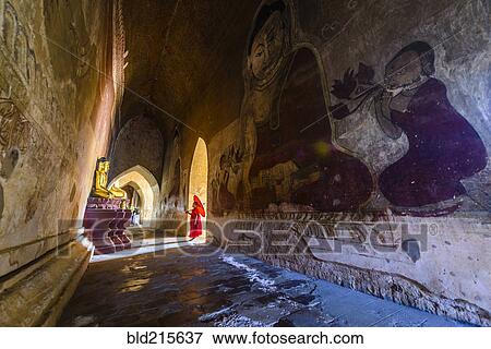 Stock Photo - Asian monk-in-training walking in dilapidated stone temple. Fotosearch