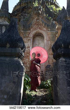 Asian monk-in-training with parasol walking on Buddhist shrine View Large Photo Image Stock Photo - Asian monk-in-training with parasol walking on Buddhist shrine. Fotosearch