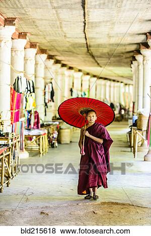 Stock Photo - Asian monk-in-training with parasol walking in hallway. Fotosearch