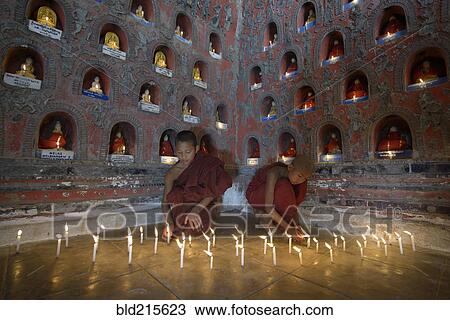 Stock Image - Asian monks-in-training lighting candles in ancient temple. Fotosearch