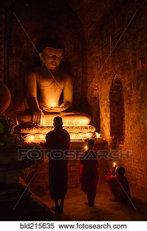Stock Photography - Asian monks-in-training lighting candles at Buddha shrine. Fotosearch