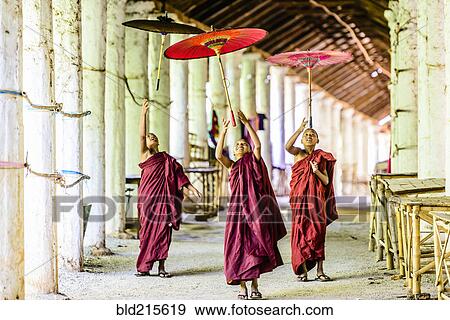 Stock Photo - Asian monks-in-training playing with parasols in hallway. Fotosearch