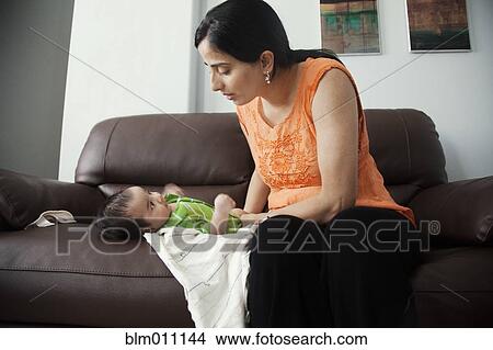 Asian mother sitting on sofa with baby boy View Large Photo Image Picture - Asian mother sitting on sofa with baby boy. Fotosearch