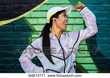 Stock Image - Asian runner standing near graffiti wall. Fotosearch