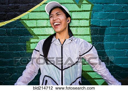Stock Image - Asian runner standing near graffiti wall. Fotosearch