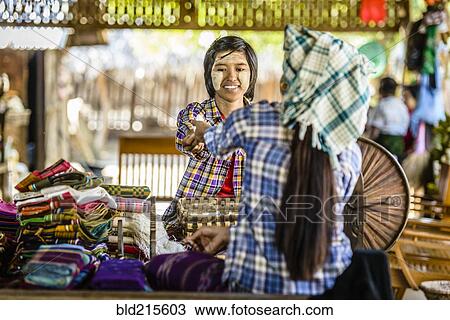 Stock Image - Asian teenage boy selling fabric at market. Fotosearch