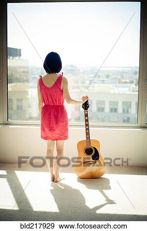 Asian woman holding guitar in window View Large Photo Image Stock Photo - Asian woman holding guitar in window. Fotosearch
