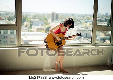 Asian woman playing guitar in window View Large Photo Image Stock Photo - Asian woman playing guitar in window. Fotosearch