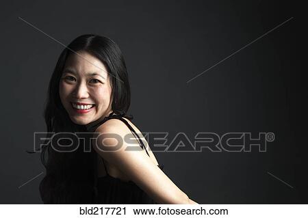 Stock Image - Asian woman smiling over her shoulder. Fotosearch