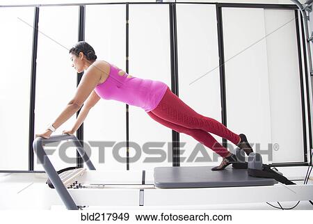 Stock Photo - Asian woman using exercise machine in gymnasium. Fotosearch