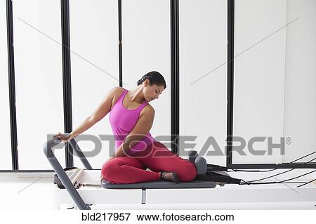 Stock Photo - Asian woman using exercise machine in gymnasium. Fotosearch