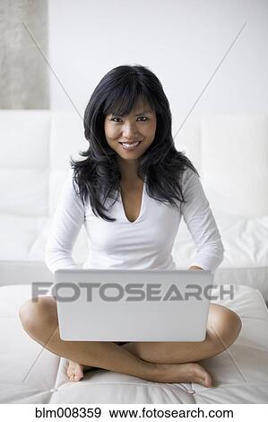Asian woman using laptop in living room View Large Photo Image Stock Photo - Asian woman using laptop in living room. Fotosearch