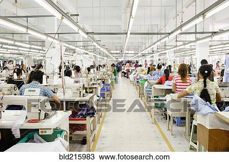 Stock Image - Asian worker sewing clothing in garment factory. Fotosearch
