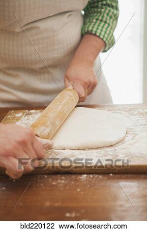 Stock Image - Baker rolling dough on counter. Fotosearch