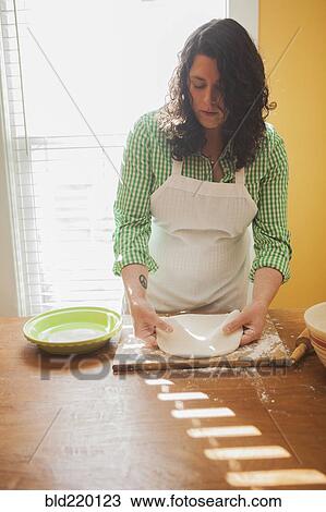 Stock Image - Baker rolling dough on counter. Fotosearch