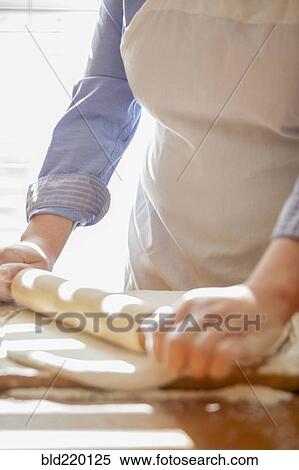 Stock Photography - Baker rolling dough on counter. Fotosearch