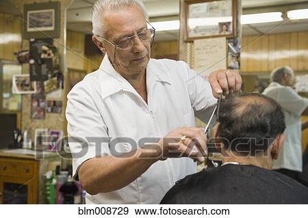 Stock Photo - Barber cutting customer's hair in barbershop. Fotosearch