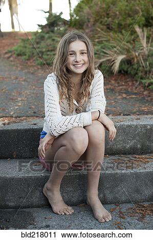 Stock Image - Barefoot girl sitting on park steps. Fotosearch