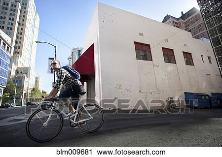 Stock Image - Bicycle messenger riding on city street. Fotosearch