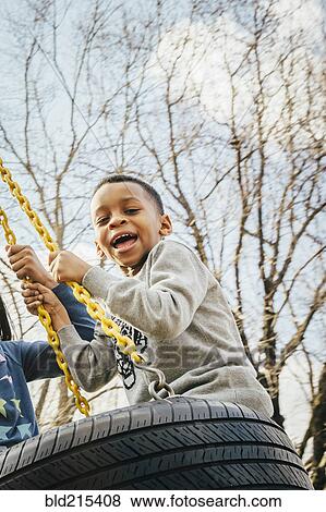 Black boy playing on tire swing View Large Photo Image Stock Photo - Black boy playing on tire swing. Fotosearch