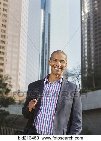 Stock Image - Black businessman standing in city. Fotosearch