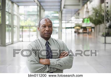 Stock Image - Black businessman standing in lobby. Fotosearch