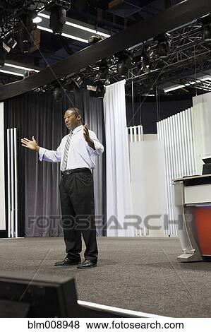 Stock Photo - Black businessman standing on stage. Fotosearch