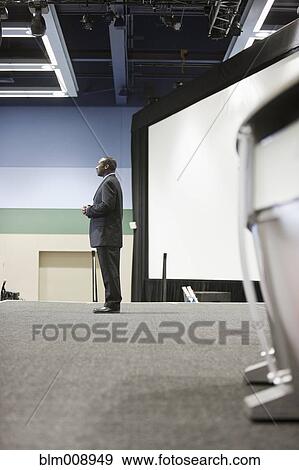 Stock Photo - Black businessman standing on stage. Fotosearch