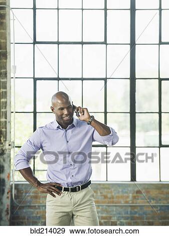 Stock Photo - Black businessman talking on cell phone in warehouse. Fotosearch