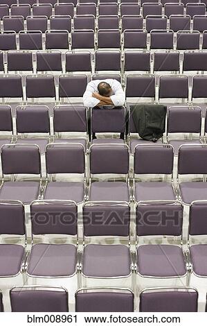 Stock Image - Black businessman waiting in empty conference center. Fotosearch